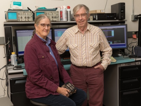 Marcia and George Rieke posing in front of computer monitors in the lab
